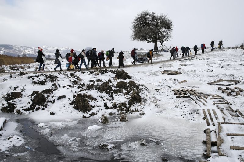 © Reuters. Imigrantes atravessam campo congelado após passar fronteira da Macedônia, perto da cidade de Miratovac, Sérvia