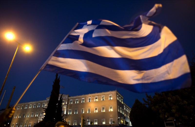 © Reuters. Greek parliament is seen behind a flag during an anti-austerity rally in Athens, Greece