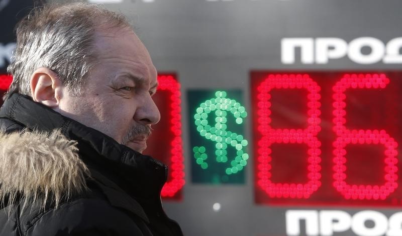 © Reuters. A man looks on near a board showing currency exchange rates of the U.S. dollar against the rouble in Moscow