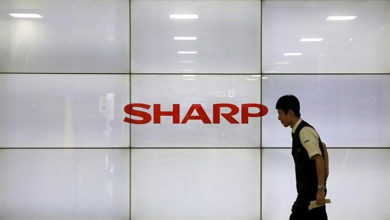 © Reuters. A man walks past display showing a logo of Sharp Corp in Tokyo
