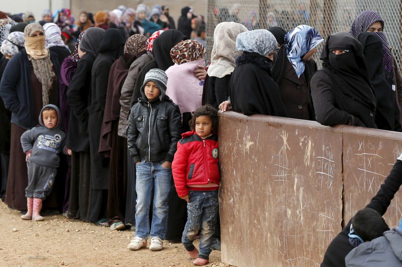 © Reuters. Syrian refugees stand in line as they wait for aid packages at Al Zaatari refugee camp