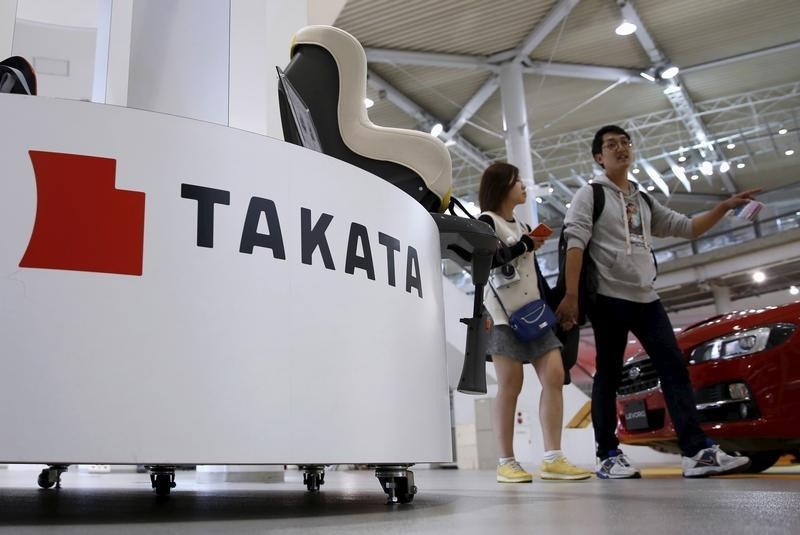 © Reuters. Visitors walk behind a logo of Takata Corp on its display at a showroom for vehicles in Tokyo