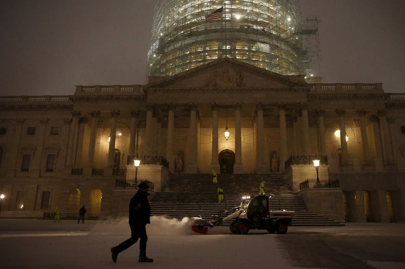 © Reuters. Workers clear falling snow from the East Front of the U.S. Capitol in Washington