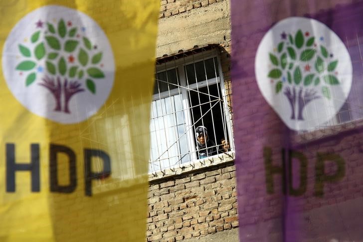 © Reuters. Woman and a boy look out of a balcony as election banners of the pro-Kurdish Peoples' Democratic Party (HDP) hang outside in Diyarbakir