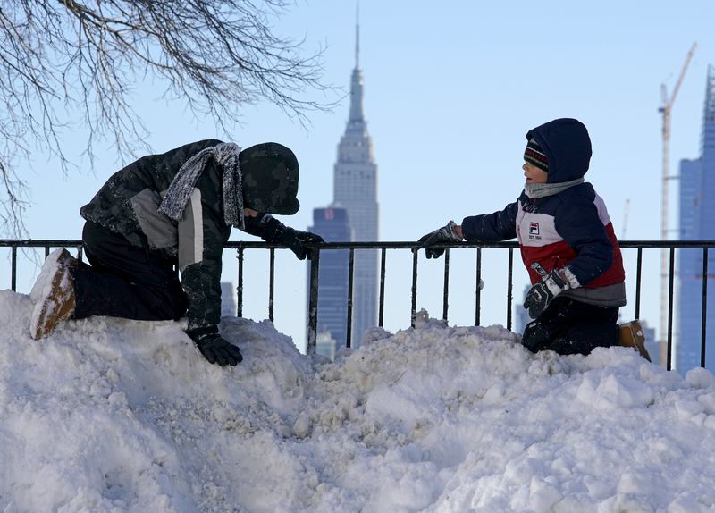 © Reuters. Two boys play atop a pile of snow at the end of a street in Union City