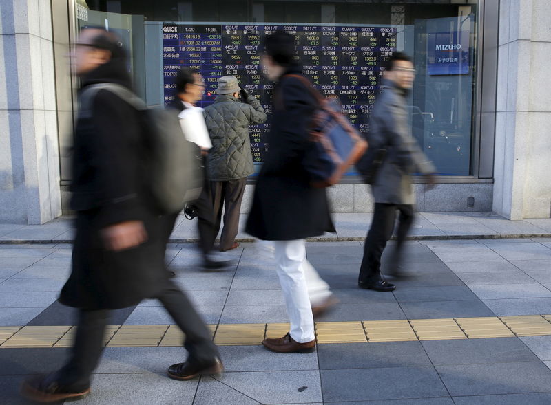 © Reuters. Man looks at an electronic stock quotation board as passers-by walk past, outside a brokerage in Tokyo