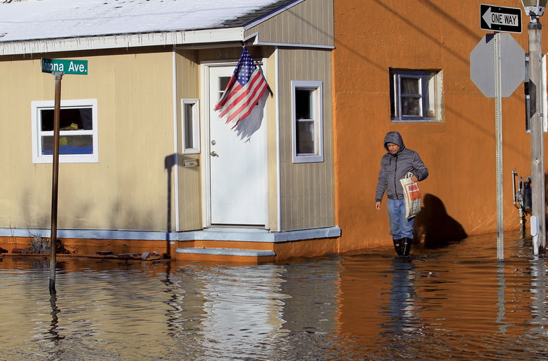 © Reuters. A man walks on a flooded street at Fairmount and Arizona Avenues on his way to work at a casino after a powerful snowstorm struck the U.S. East Coast, in Atlantic City, New Jersey