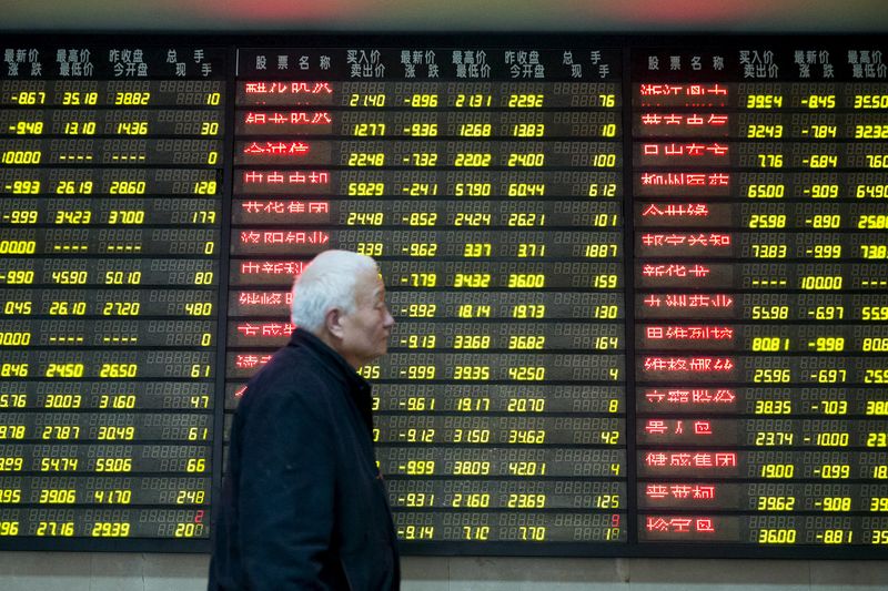 © Reuters. Investidor passa por painel eletrônico com informações de ações em corretora de Nanjing, na China