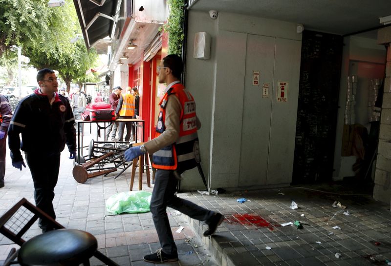 © Reuters. A file picture shows rescue personnel walking next to blood stains at the scene of a shooting rampage by Israeli Arab Nashat Melhem at a bar in Tel Aviv, Israel