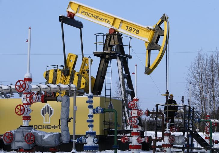 © Reuters. Worker looks at pump jack at Rosneft company owned Samotlor oil field outside West Siberian city of Nizhnevartovsk