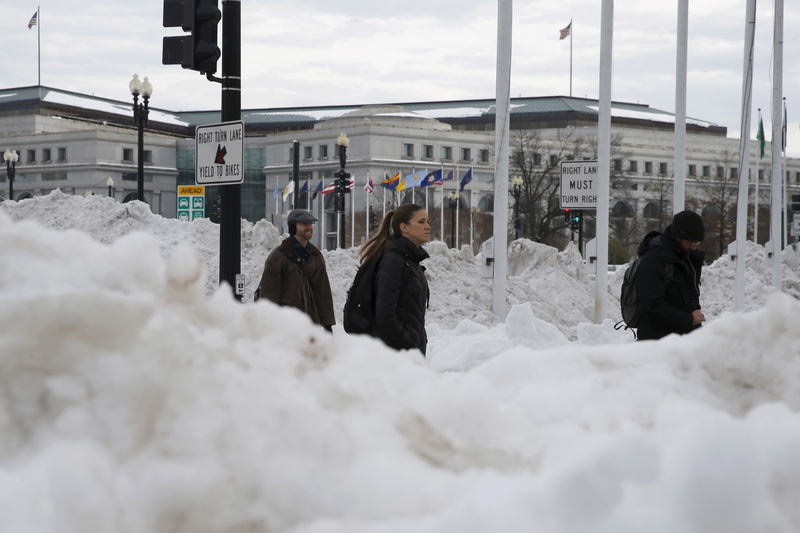© Reuters. People make their way through piles of plowed snow in Washington