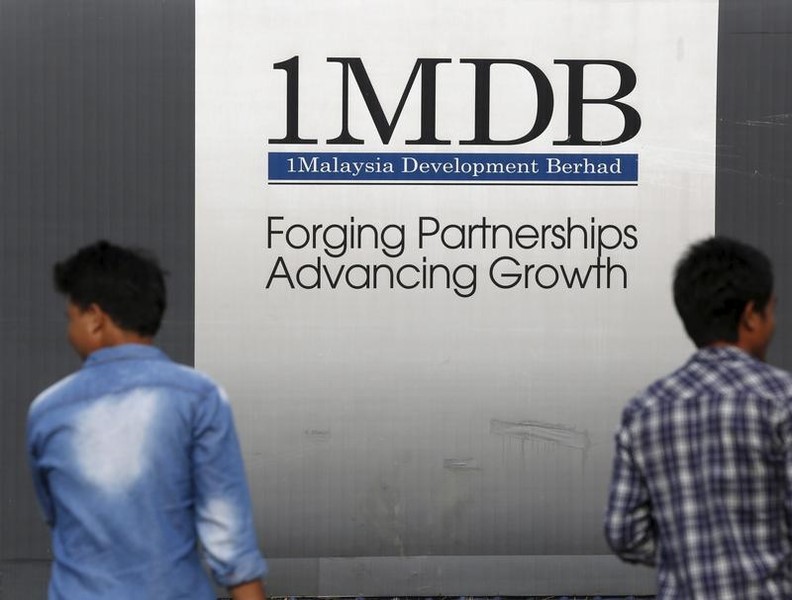 © Reuters. Men walk past a 1 Malaysia Development Berhad (1MDB) billboard at the funds flagship Tun Razak Exchange development in Kuala Lumpur, Malaysia