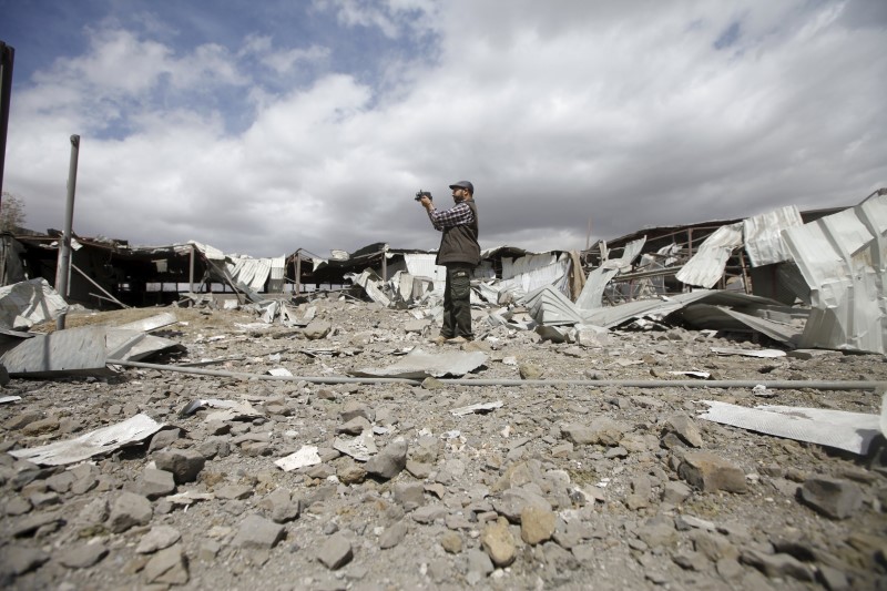 © Reuters. A man records damage at a tea factory after it was hit by Saudi-led air strikes in Yemen's capital Sanaa