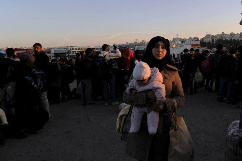 © Reuters. A migrant carries a baby as refugees and migrants arrive aboard the passenger ferry Blue Star1 at the port of Piraeus, near Athens