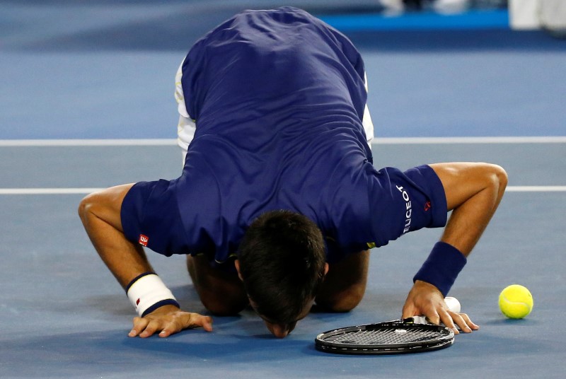 © Reuters. El tenista serbio Novak Djokovic besa el suelo mientras celebra su triunfo en la final del Abierto de Australia contra el escocés Andy Murray, en Melbourne