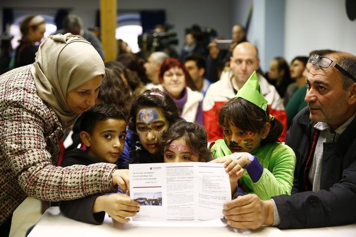 © Reuters. Syrian family read information leaflets on social etiquette ahead of the carnival season at refugee camp in Mainz