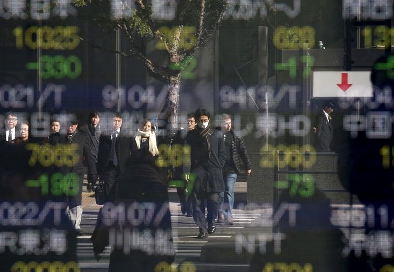 © Reuters. People are reflected in a stock quotation board outside a brokerage in Tokyo