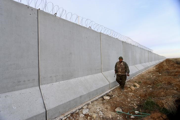 © Reuters. A Kurdish People's Protection Units (YPG) fighter walks near a wall, which activists said was put up by Turkish authorities, on the Syria-Turkish border in the western countryside of Ras al-Ain, Syria
