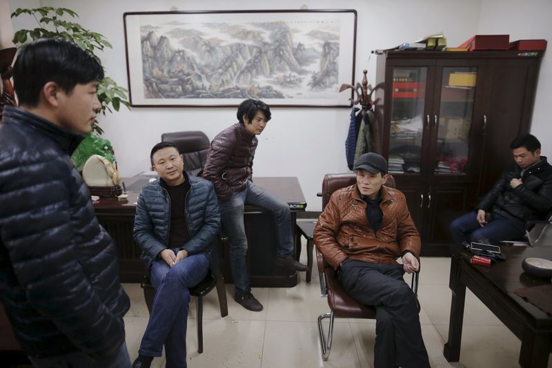 © Reuters. Migrant workers pass time at the offices of a subcontractor company at the construction site of Zixia Garden development complex in Qianan, Tangshan City