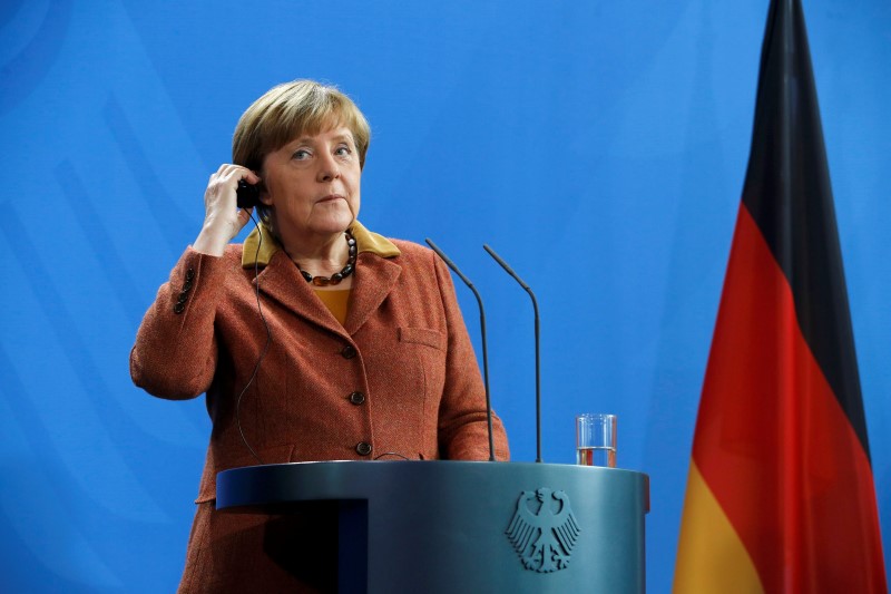 © Reuters. German Chancellor Merkel adjusts her earpiece during a news conference at the Chancellery in Berlin