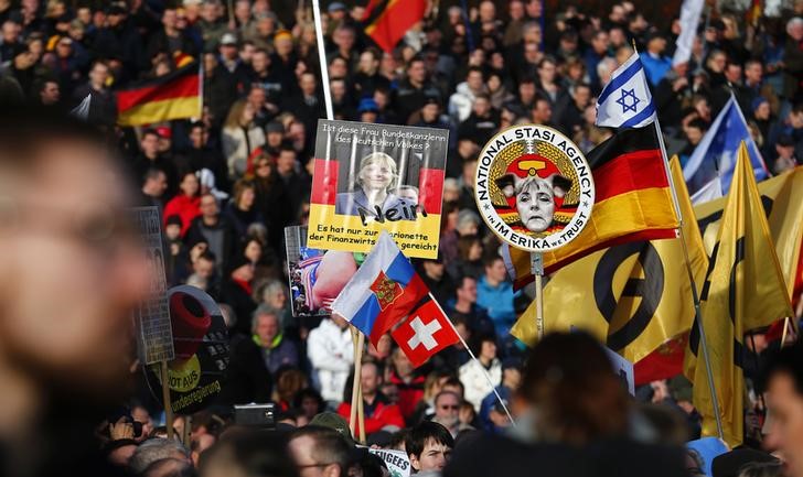 © Reuters. Supporters of the anti-Islam movement PEGIDA hold posters depicting German Chancellor Merkel during a demonstration in Dresden
