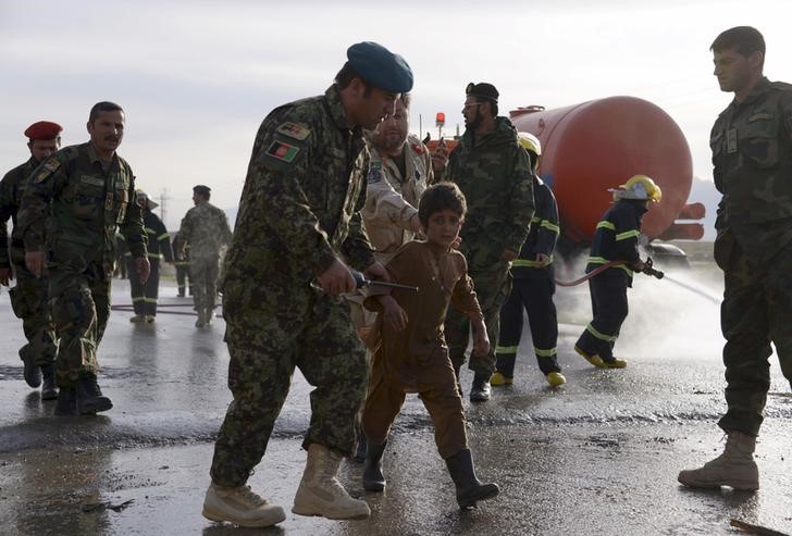 © Reuters. An Afghan National Army officer escorts a slightly injured boy from the site of a suicide attack on the outskirts of Mazar-i-Sharif, Afghanistan