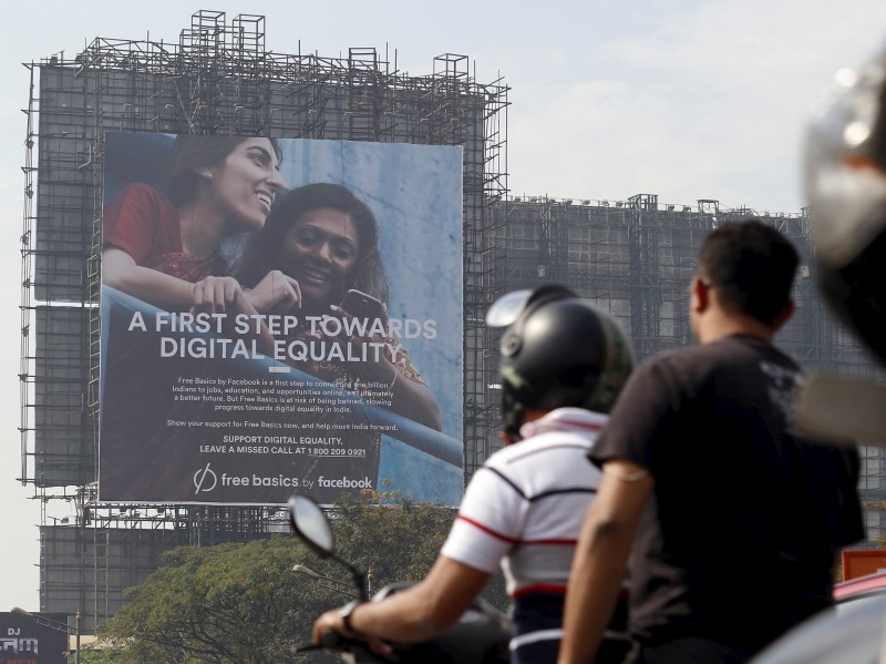 © Reuters. Motorists ride past a billboard displaying Facebook's Free Basics initiative in Mumbai, India