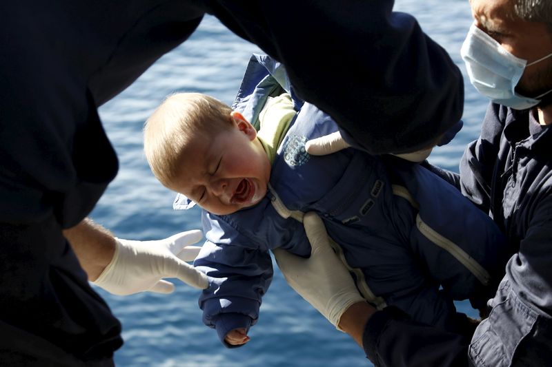 © Reuters. Greek Coast Guard officers move a baby from a dinghy carrying refugees and migrants aboard the Ayios Efstratios Coast Guard vessel,  during a rescue operation in open sea between the Turkish coast and the Greek island of Lesbos