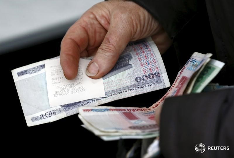 © Reuters. A woman holds Belarussian roubles as she buys products at the Belarussian Republican Union of Consumer Societies' mobile shop on the outskirts of Minsk