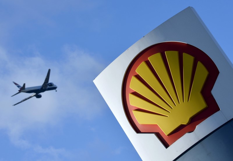 © Reuters. File photo of passenger plane flies over a Shell logo at a petrol station in west London