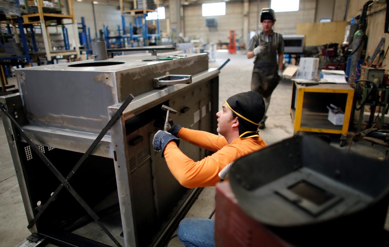 © Reuters. A worker checks a metal furnace before welding it in a factory in Gravellona Lomellina