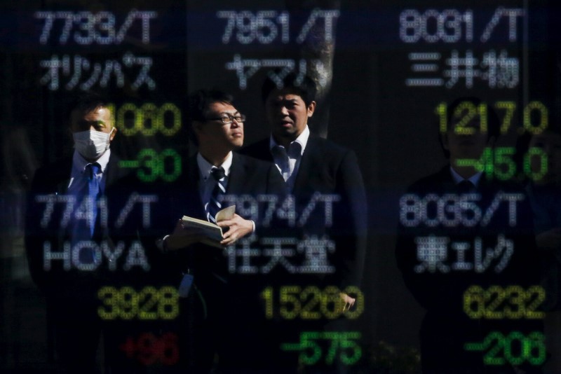 © Reuters. People are reflected in a display showing market indices outside a brokerage in Tokyo