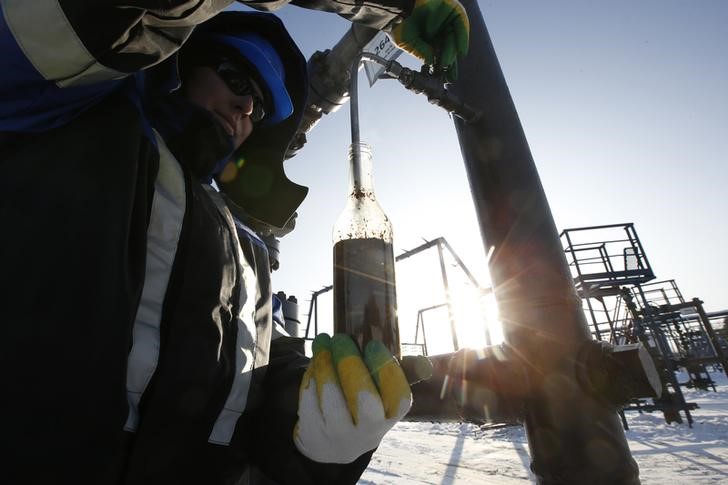© Reuters. Рабочий берет образец нефти с Южно-Приобского месторождения Газпромнефти в Западной Сибири