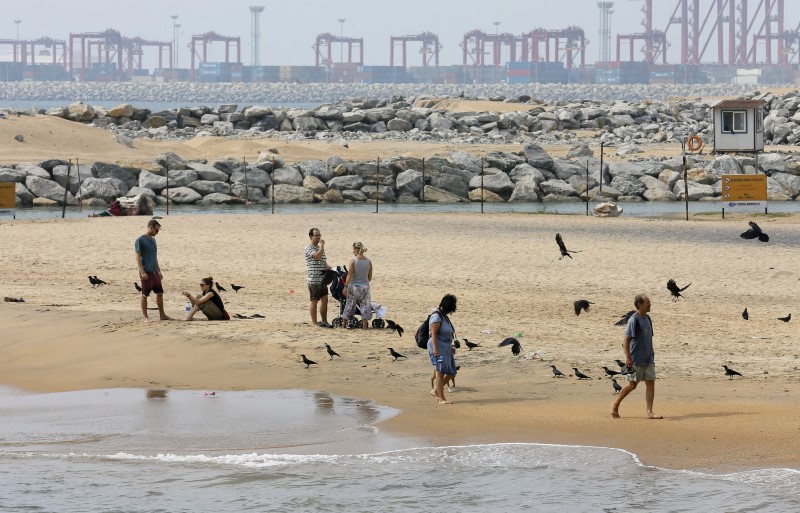 © Reuters. Tourists rest near the "Colombo Port City" construction site, backed by Chinese investment, in Colombo
