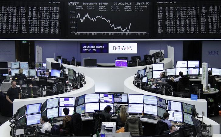 © Reuters. Traders work at their desks in front of the German share price index, DAX board, at the stock exchange in Frankfurt