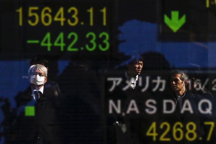 © Reuters. People are reflected in a display showing market indices outside a brokerage in Tokyo
