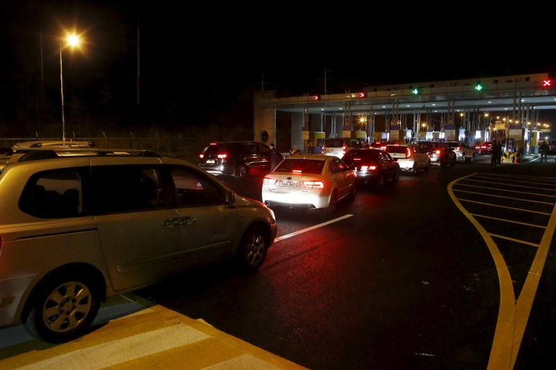 © Reuters. South Korean vehicles transporting employees working at the Kaesong Industrial Complex (KIC) wait to pass the gateway at the South's CIQ in Paju