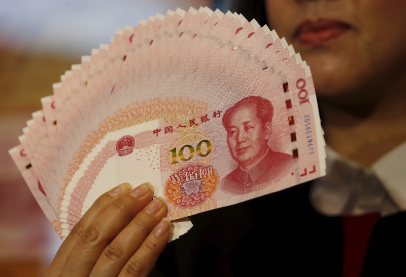 © Reuters. A staffer poses with 2015 edition of the 100 renminbi notes at the Bank of China Tower in Hong Kong