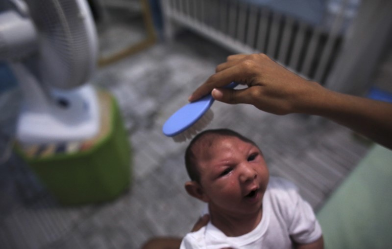 © Reuters. Daniele Santos combs the hair of her son Juan Pedro who is 2-months old and born with microcephaly after bathing him at their house in Recife