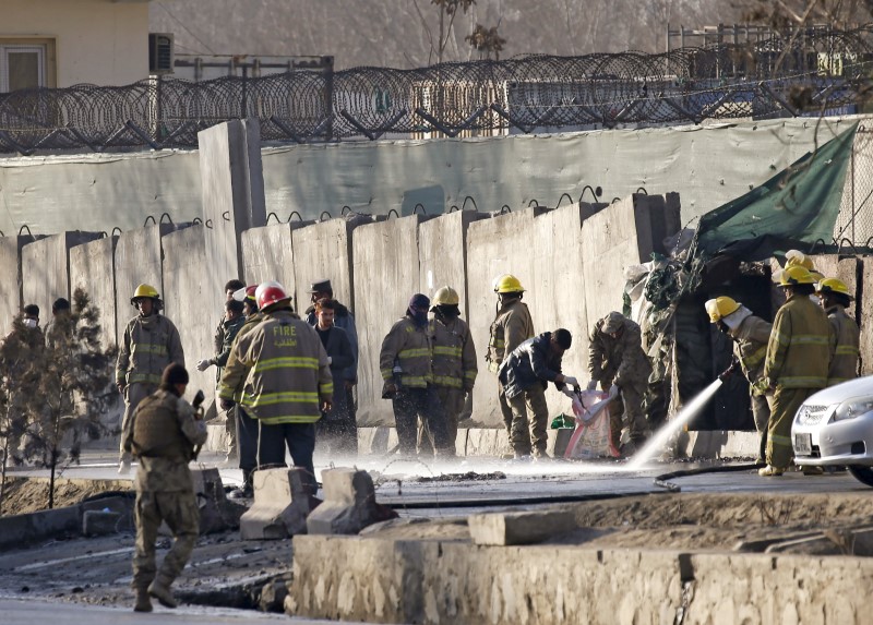 © Reuters. Afghan fire-fighters and members of security forces clean the site of a suicide attack in Kabul, Afghanistan