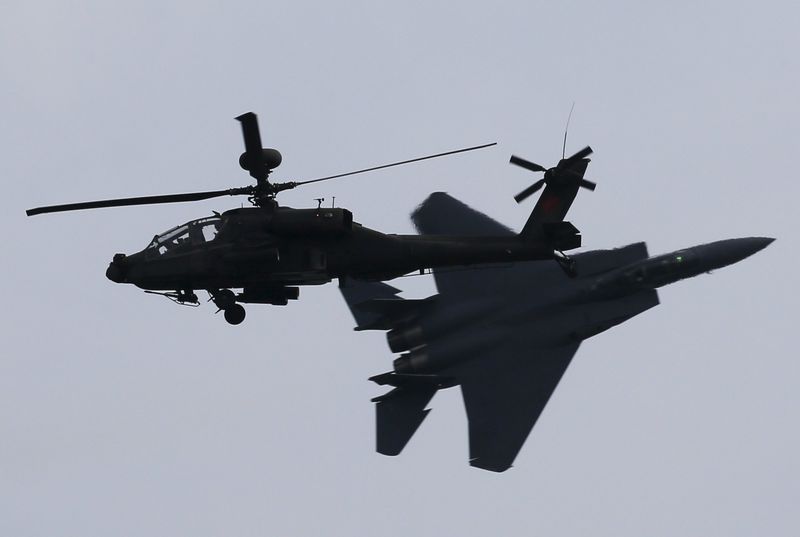 © Reuters. A Republic of Singapore Air Force (RSAF) F-15SG fighter aircraft performs a maneuver as it flies past an RSAF AH-64D Apache helicopter during a preview of the Singapore Airshow at Changi exhibition center in Singapore 
