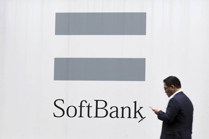 © Reuters. A man looks at his phone as he walks past an advertising poster of the SoftBank telecommunications company in Tokyo