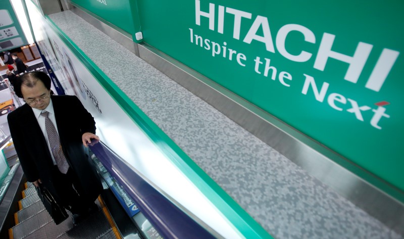 © Reuters. A shopper rides an escalator past a logo of Hitachi Corp at an electronics retail store in Tokyo