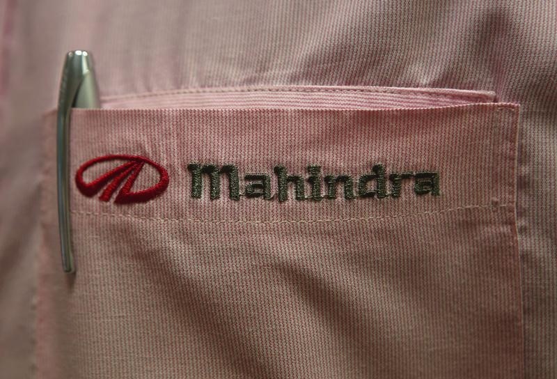 © Reuters. The logo of Mahindra & Mahindra Ltd is pictured on the pocket of a salesman's shirt as he poses inside the company's showroom in Mumbai