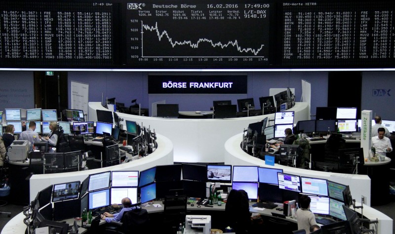 © Reuters. Traders work at their desks in front of the German share price index, DAX board, at the stock exchange in Frankfurt