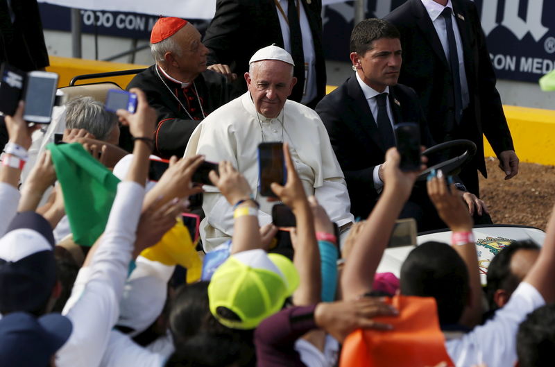 © Reuters. People take photographs of Pope Francis during a meeting with youths at the Jose Maria Morelos y Pavon stadium in Morelia, Mexico