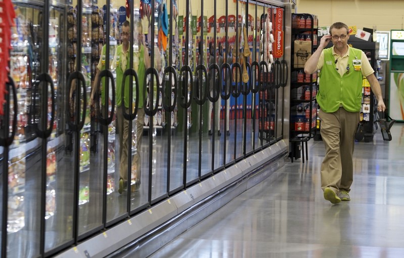 © Reuters. A Wal-Mart employee is reflected in the cold cases at the Wal-Mart Neighborhood Market in Bentonville

