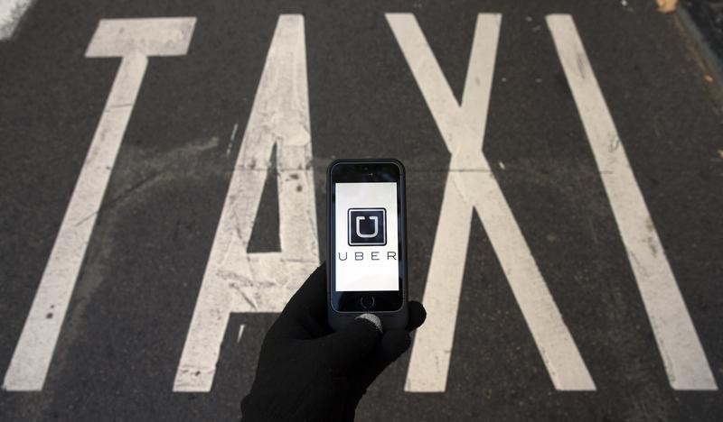 © Reuters. Photo illustration of logo of car-sharing service app Uber on a smartphone over a reserved lane for taxis in a street in Madrid