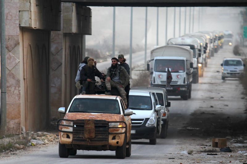 © Reuters. Rebel fighters escort a Syrian Arab Red Crescent aid convoy heading towards the villages of al-Foua and Kefraya in Idlib province