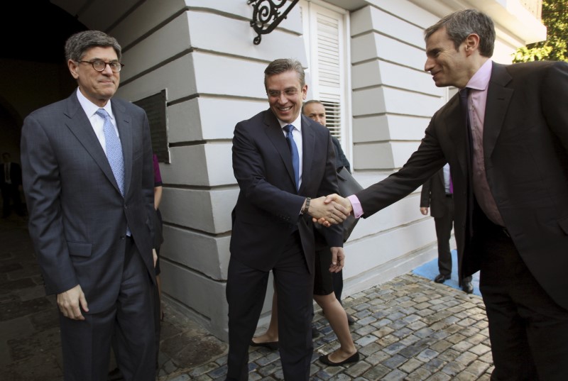 © Reuters. U.S. Treasury Secretary Lew looks on as Puerto Rico's Governor Garcia Padilla shakes hands with Counselor to the Secretary Weiss in San Juan